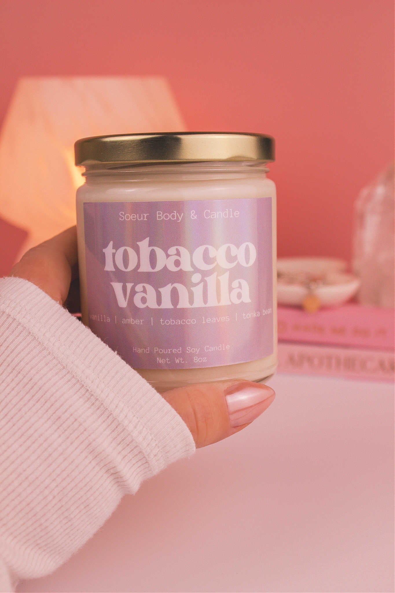 Close-up of a hand holding the Tobacco Vanilla candle, showcasing its design and fragrance notes of vanilla, amber, tobacco leaves, and tonka bean.
