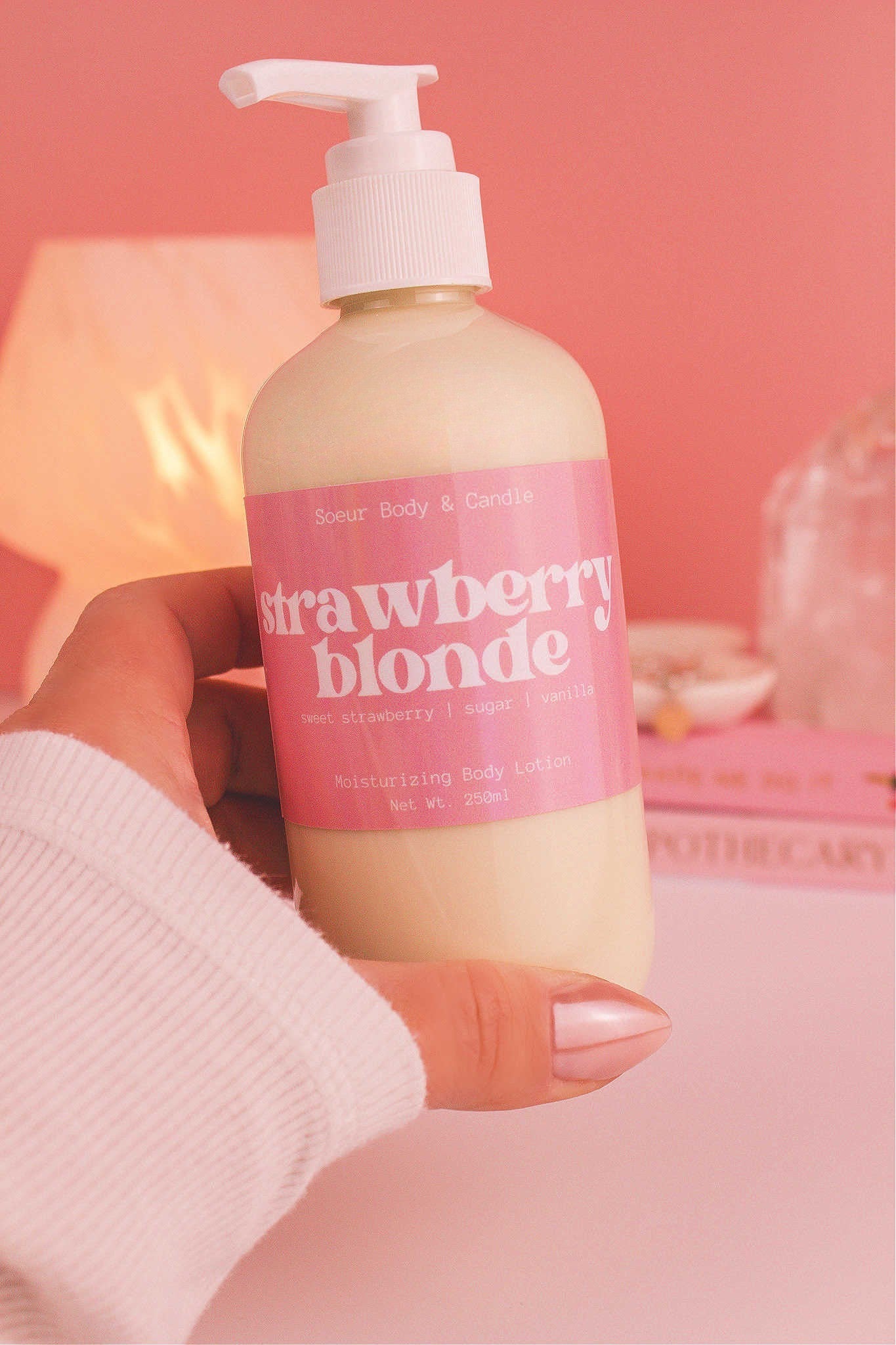 Close-up of a hand holding the Strawberry Blonde body lotion, highlighting its smooth texture and refreshing scent of sweet strawberry, sugar, and vanilla.