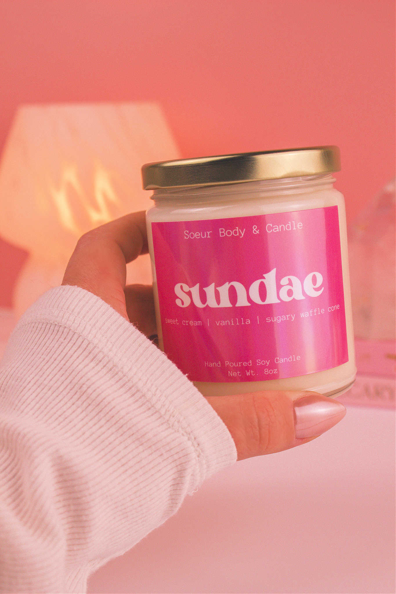 Close-up of a hand holding the Sundae candle, showcasing its design and fragrance notes of sweet cream, vanilla, and sugary waffle cone.