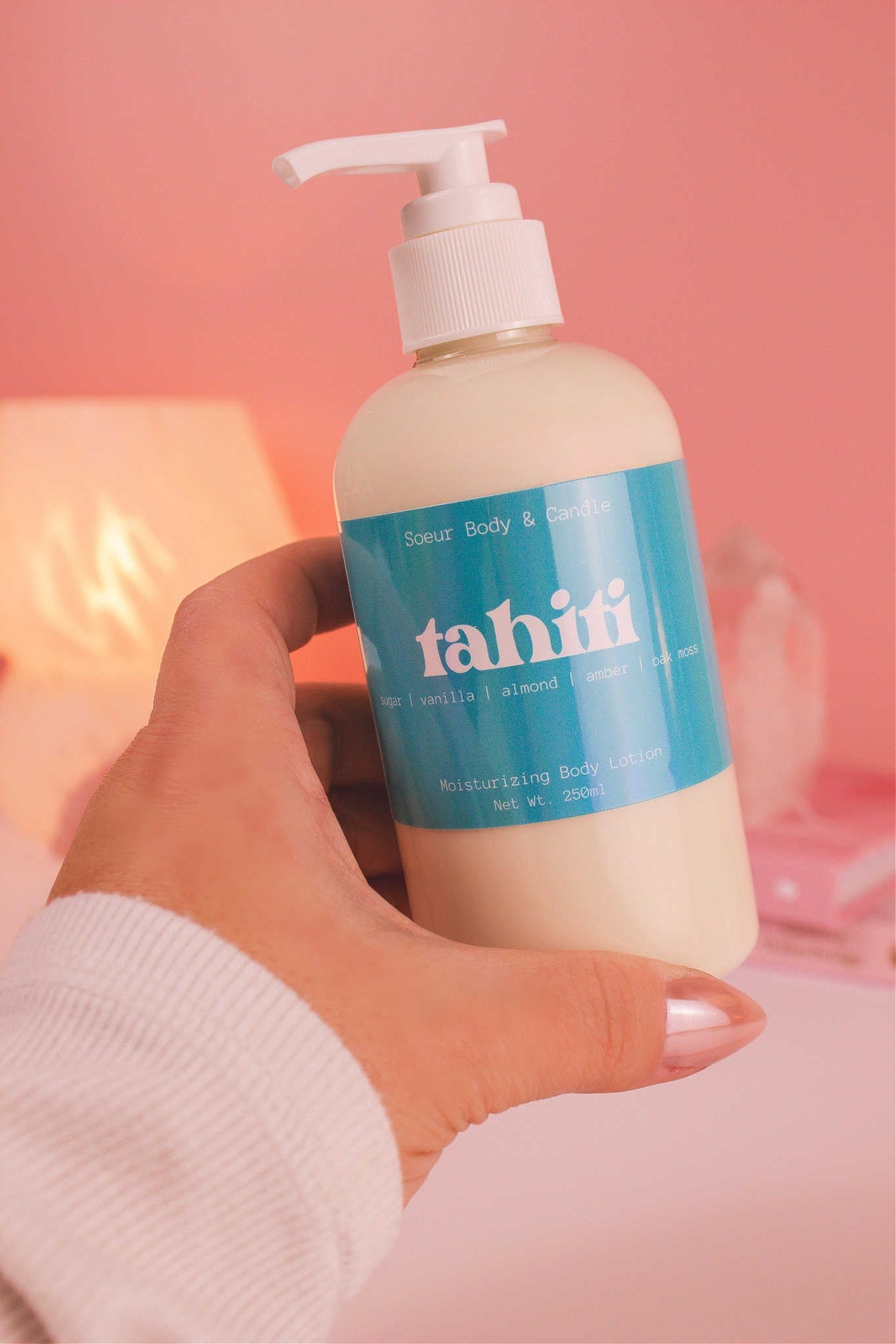 Close-up of a hand holding the Tahiti body lotion, highlighting its smooth texture and refreshing scent of sugar, vanilla, almond, amber, and oak moss.