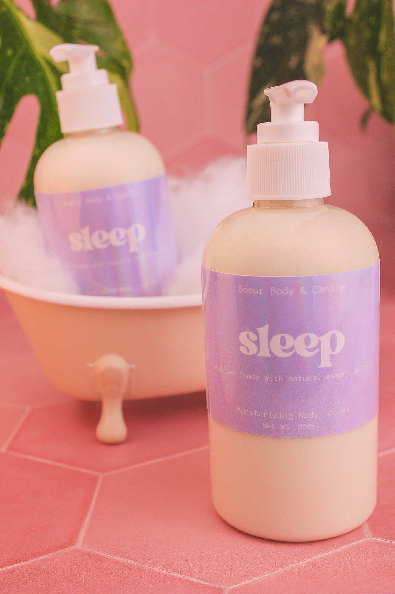 Display of two Sleep body lotions in a small tub with bubbles and plants in the background, evoking a relaxing vibe with a lavender essential oil scent.