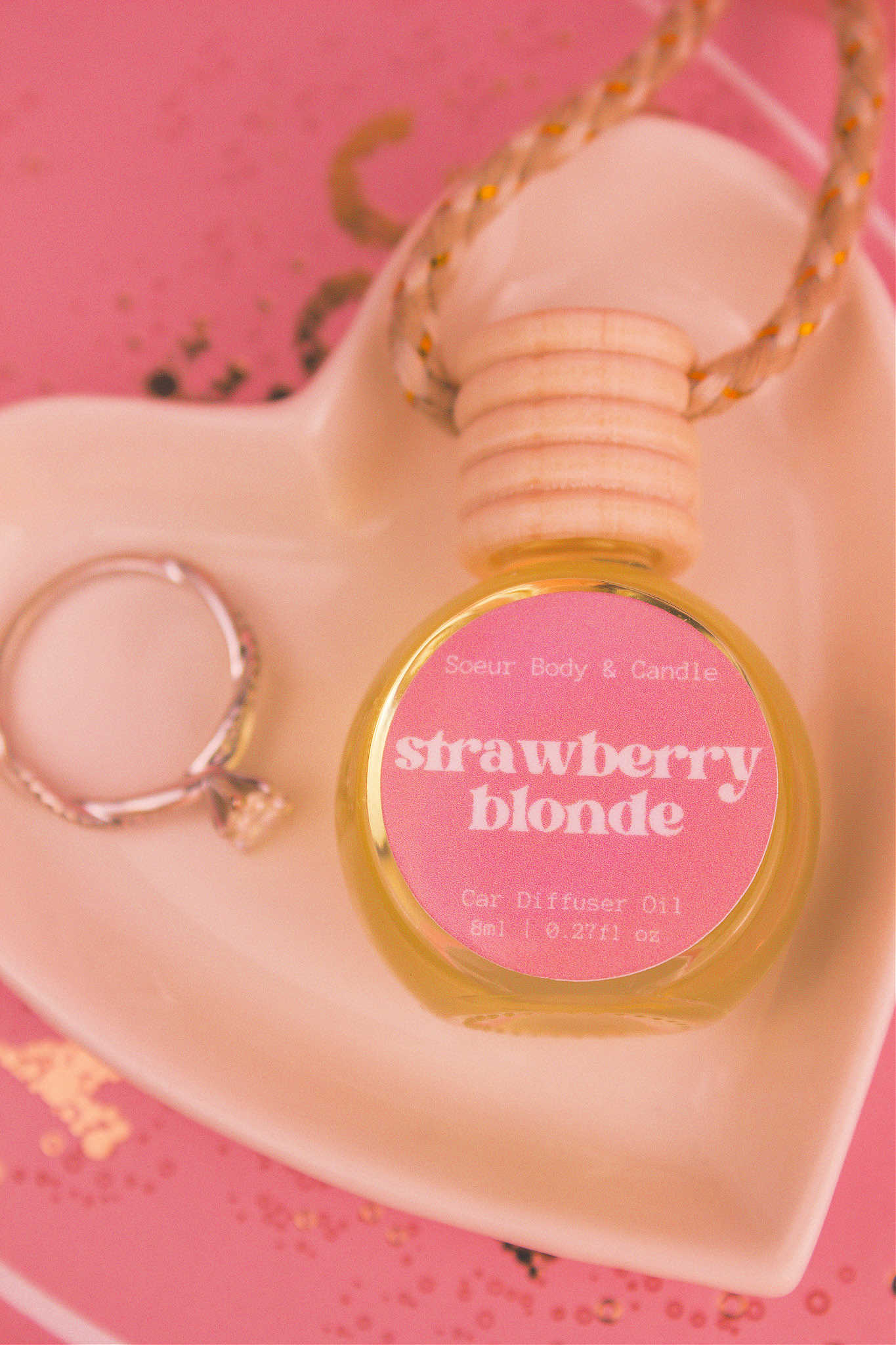 Close-up of Strawberry Blonde car diffuser in a jewelry dish with a ring beside it, featuring a delicious blend of sweet strawberry, sugar, and vanilla.