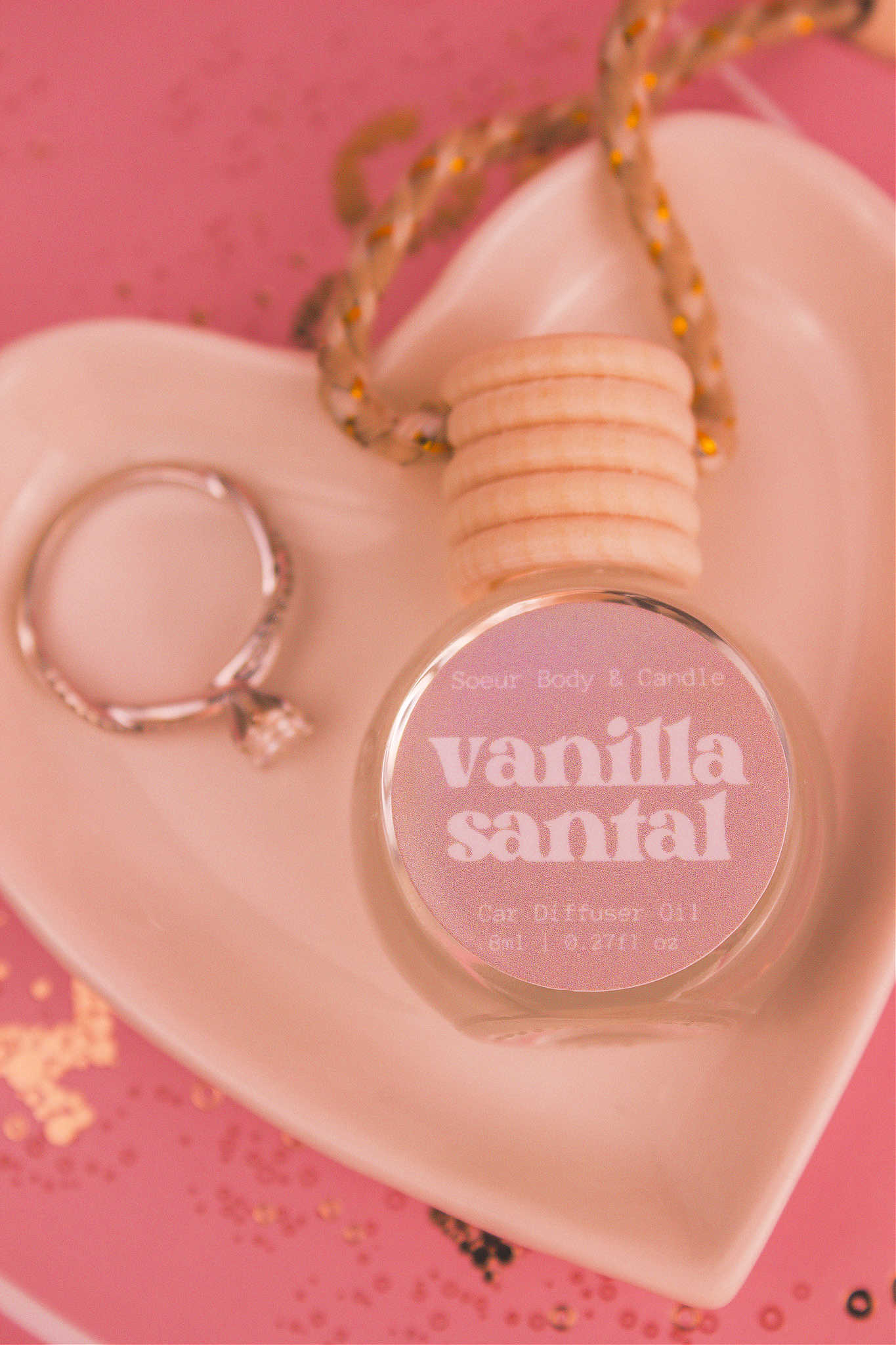 Close-up of Vanilla Santal car diffuser in a jewelry dish with a ring beside it, featuring notes of shea butter, coconut, vanilla, and sandalwood.