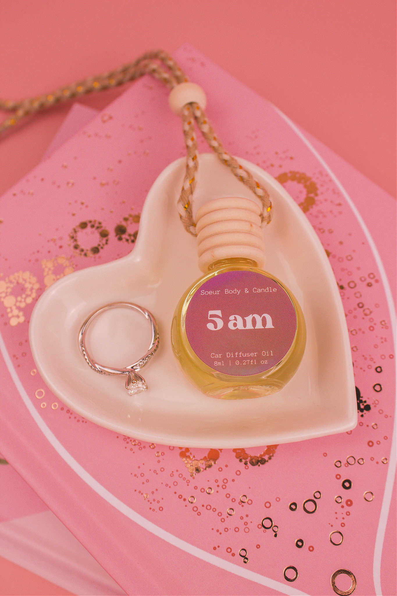 5am car diffuser in a jewelry dish with a ring beside it, sitting on top of books, featuring notes of roasted espresso, sweet vanilla, and hazelnut.