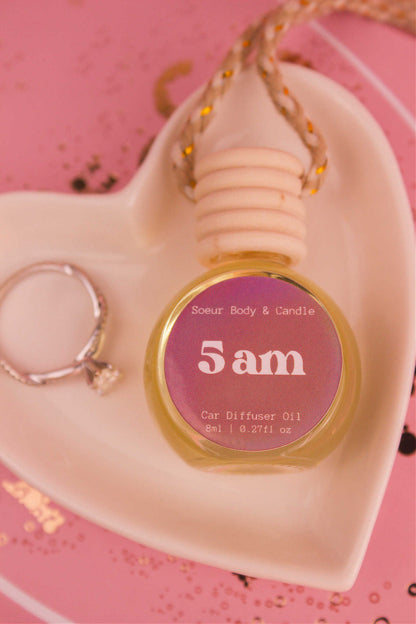 Close-up of 5am car diffuser in a jewelry dish with a ring beside it, featuring notes of roasted espresso, sweet vanilla, and hazelnut.