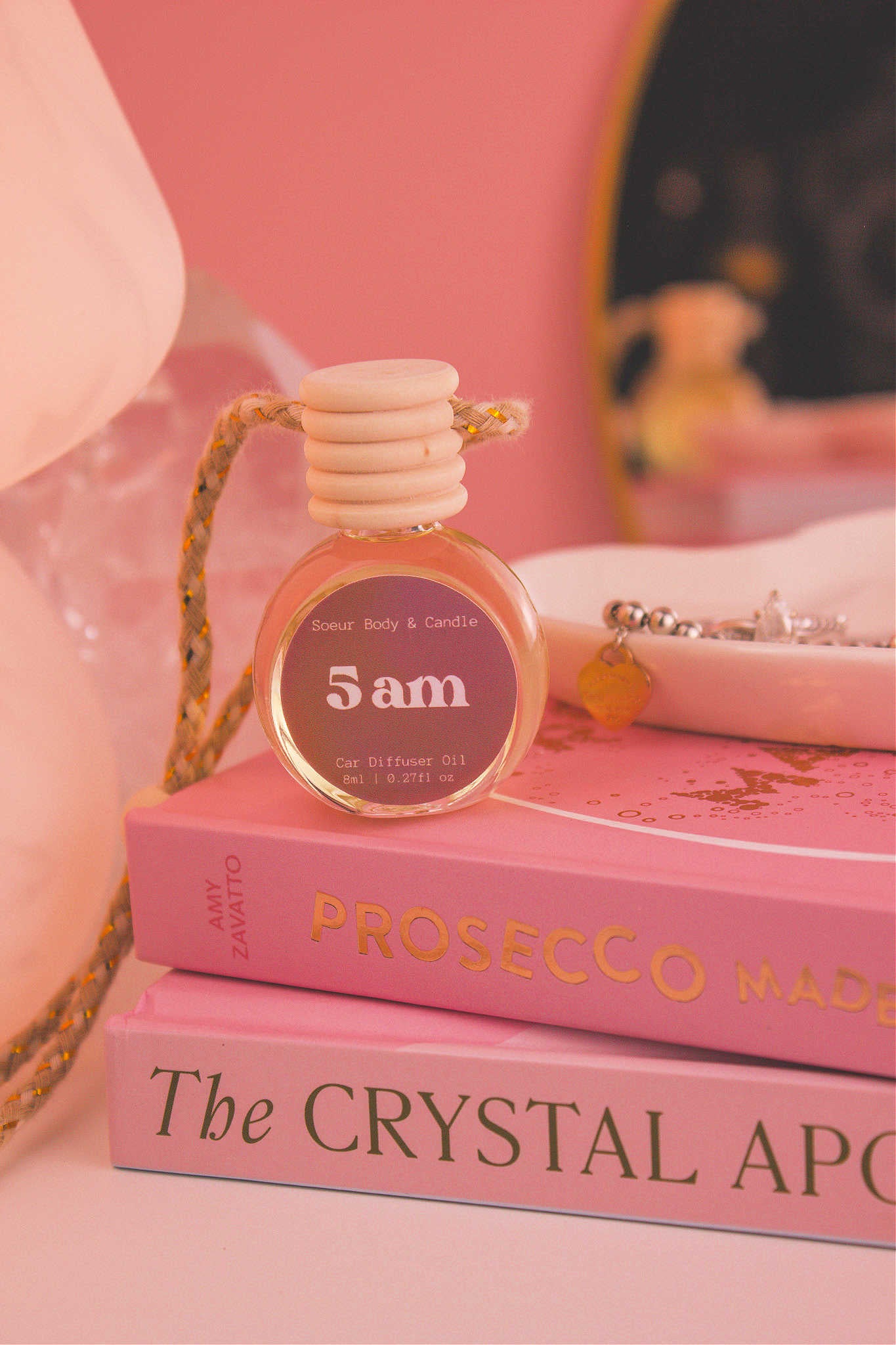 5am diffuser sitting on top of a stack of books with a jewelry dish in the background, set against a lamp, mirror, and crystals; fragrance notes: roasted espresso, sweet vanilla, hazelnut.