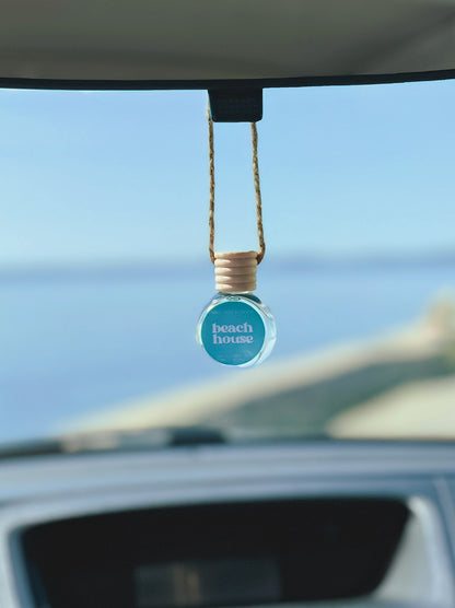 Beach House Diffuser Oil hanging from a rearview mirror, offering a balanced, long-lasting fragrance of citrus fruits, coconut, creamy vanilla, and musk—a dupe of Pink Sands by Yankee Candle. Perfect for cars, closets, lockers, and more.