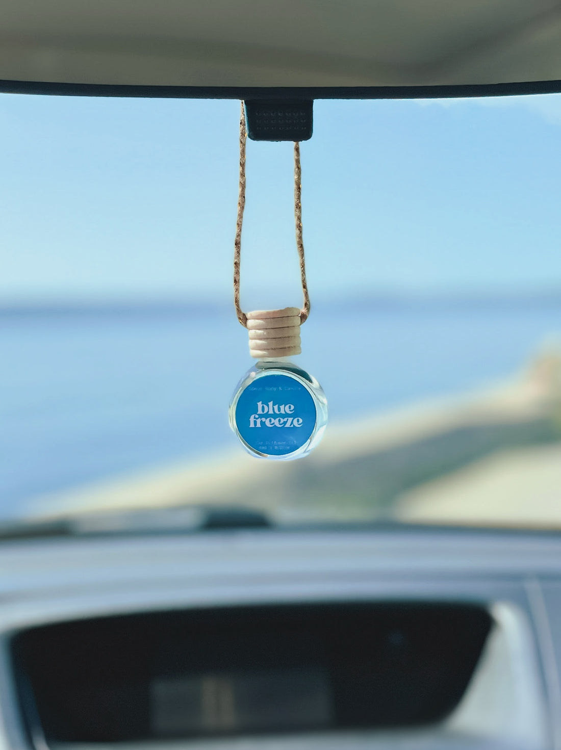 Blue Freeze Diffuser Oil hanging from a rearview mirror, offering a balanced, long-lasting fragrance of blue raspberry, strawberry, and sugar. Perfect for cars, closets, lockers, and more.