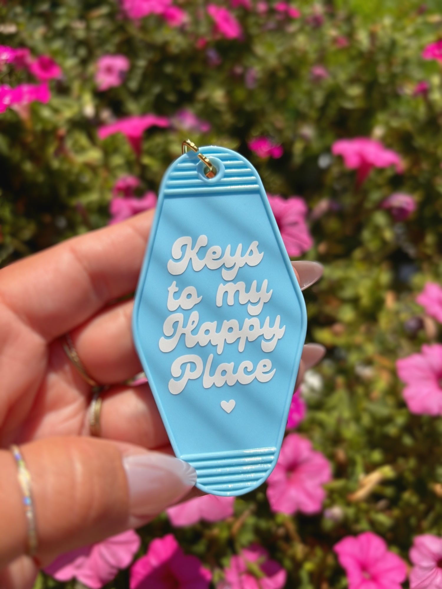 A hand holding a light blue motel-style keychain featuring the phrase &