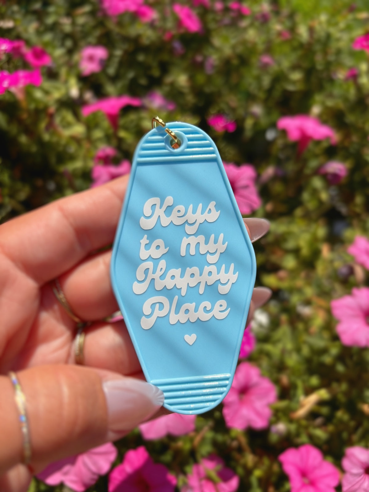 A hand holding a light blue motel-style keychain featuring the phrase &