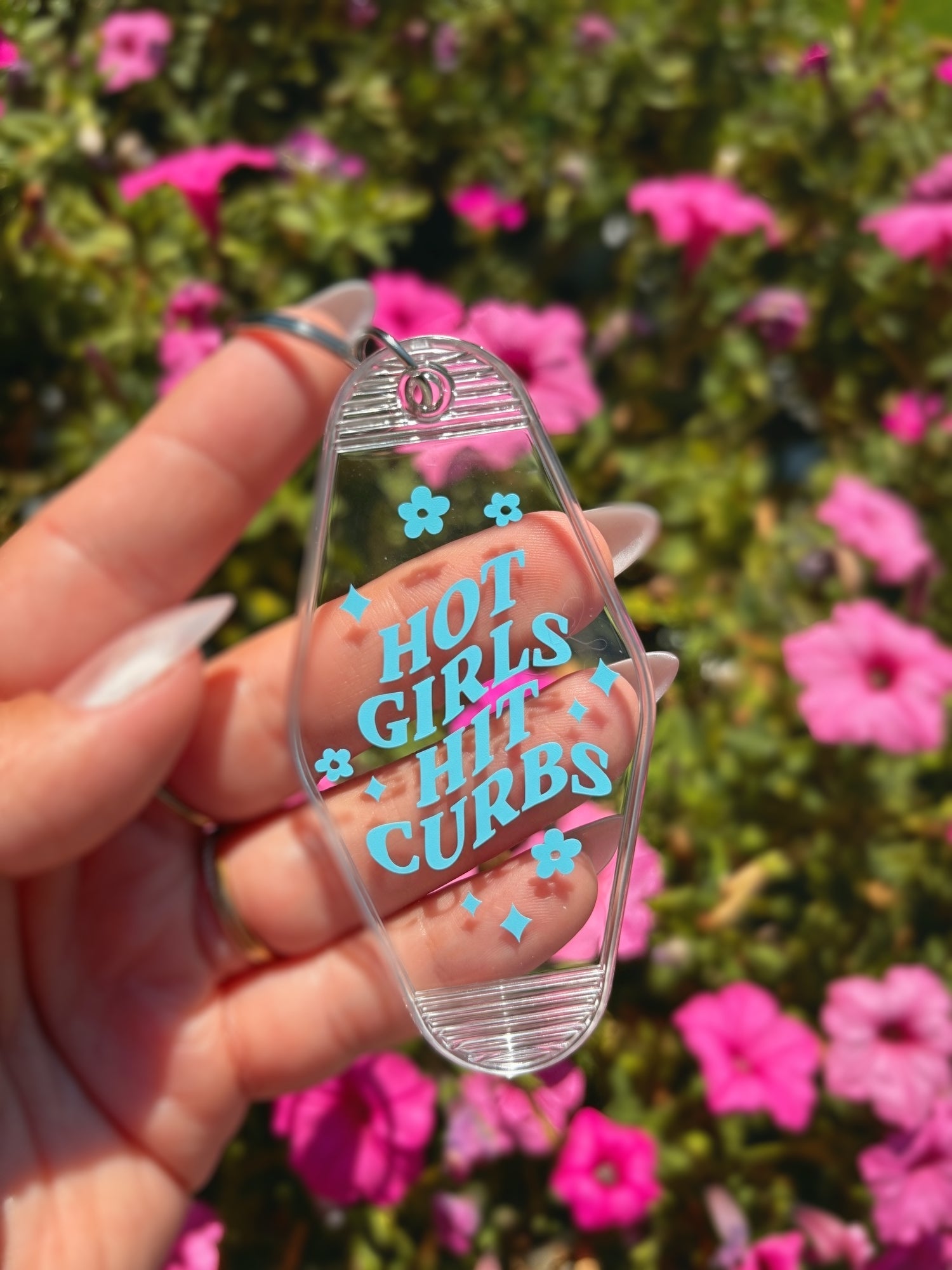 A hand holds a clear motel-style keychain featuring the text &