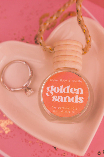 Close-up of Golden Sands car diffuser in a jewelry dish with a ring beside it, featuring fresh air, lemon, sandalwood, and vanilla notes.