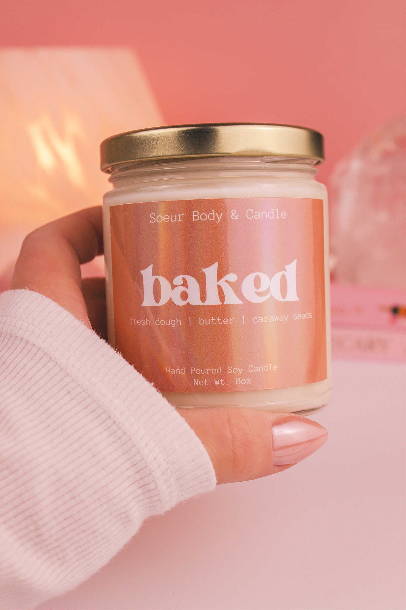 Close-up of a hand holding the Baked candle, showcasing its design and fragrance notes of fresh dough, butter, and caraway seeds.