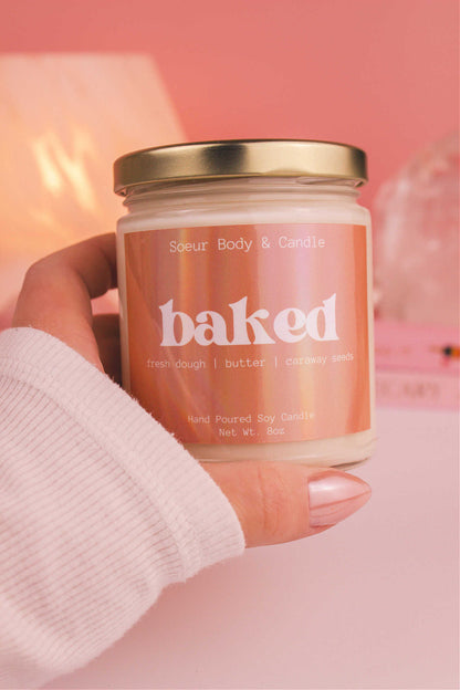 Close-up of a hand holding the Baked candle, showcasing its design and fragrance notes of fresh dough, butter, and caraway seeds.