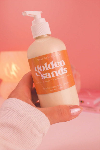 Close-up of a hand holding the Golden Sands body lotion, highlighting its smooth texture and refreshing scent of fresh air, lemon, sandalwood, and vanilla.