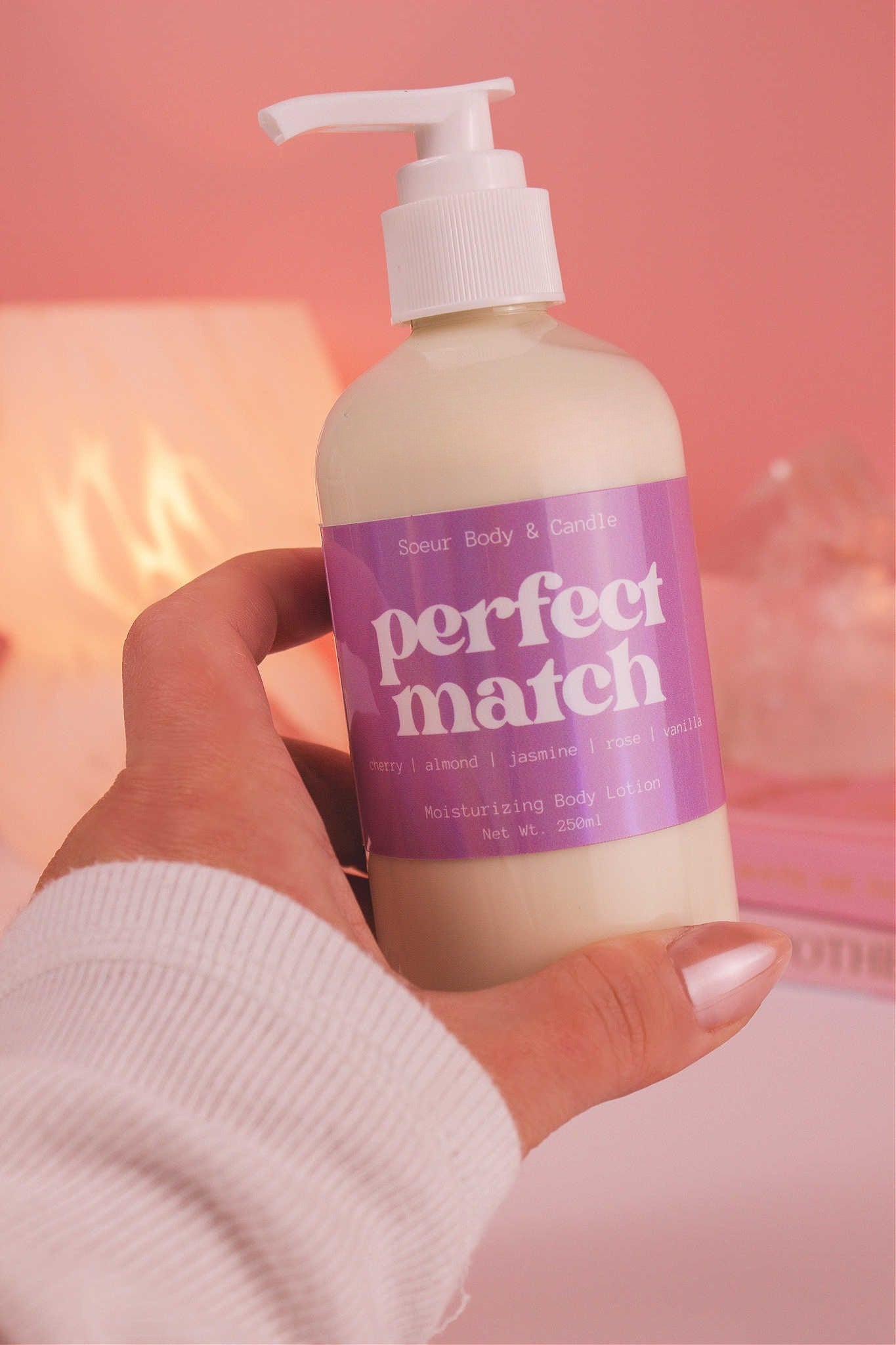 Close-up of a hand holding the Perfect Match body lotion, highlighting its smooth texture and sweet scent of cherry, almond, jasmine, rose, and vanilla.