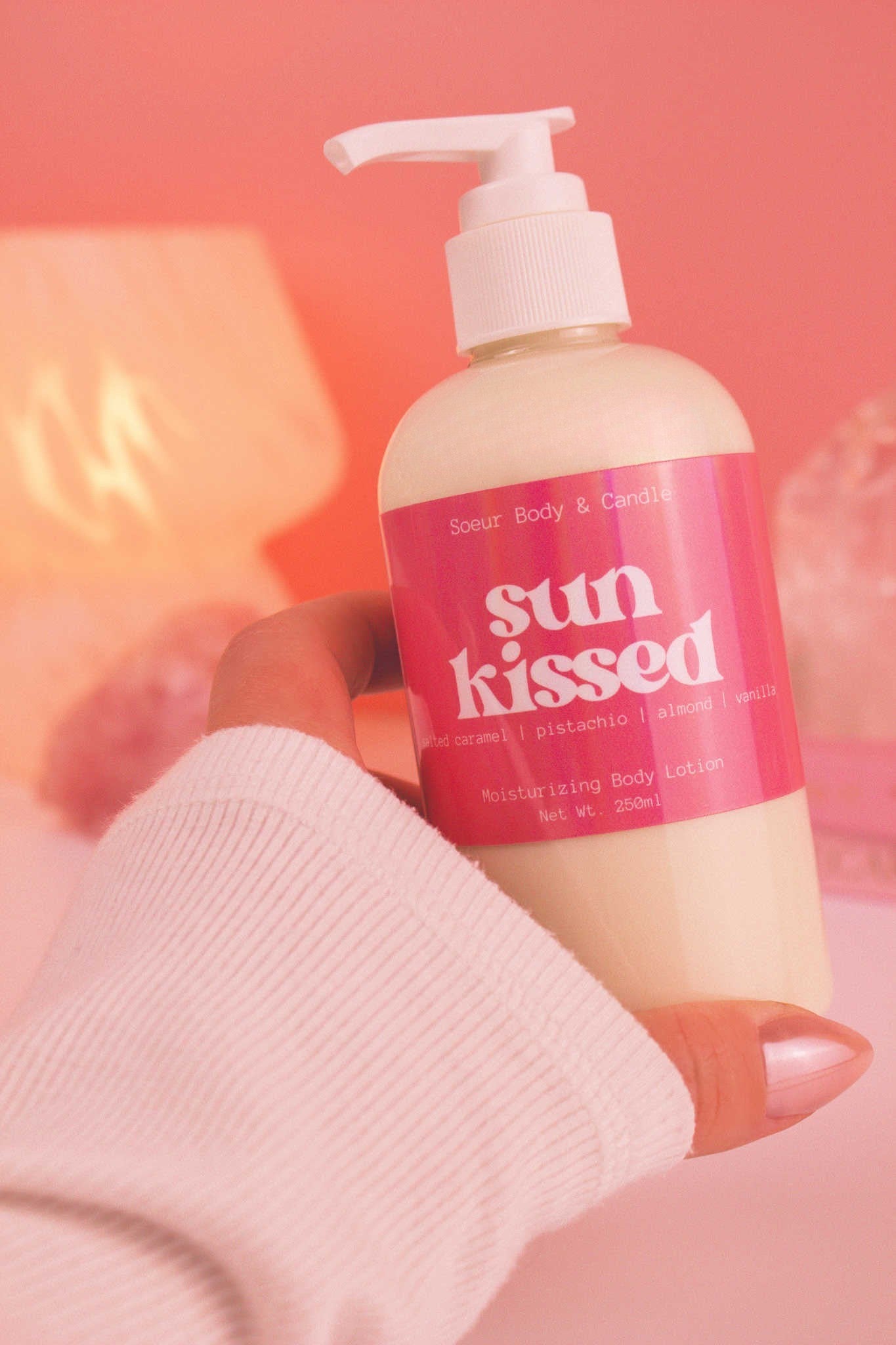 Close-up of a hand holding the Sun Kissed body lotion, highlighting its smooth texture and refreshing scent of salted caramel, pistachio, almond, and vanilla.