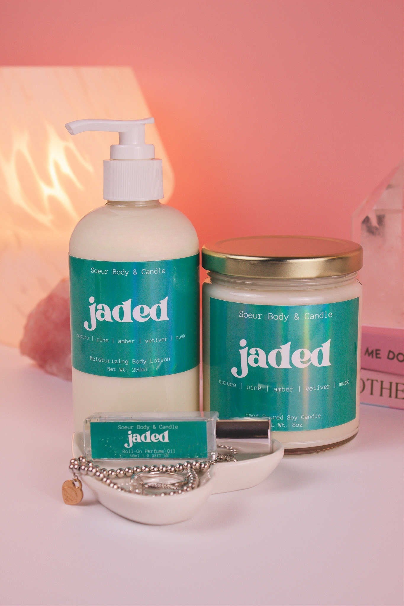 Jaded roll-on perfume, lotion, and candle together, evoking its bold, earthy fusion of spruce, pine, amber, vetiver, and musk.