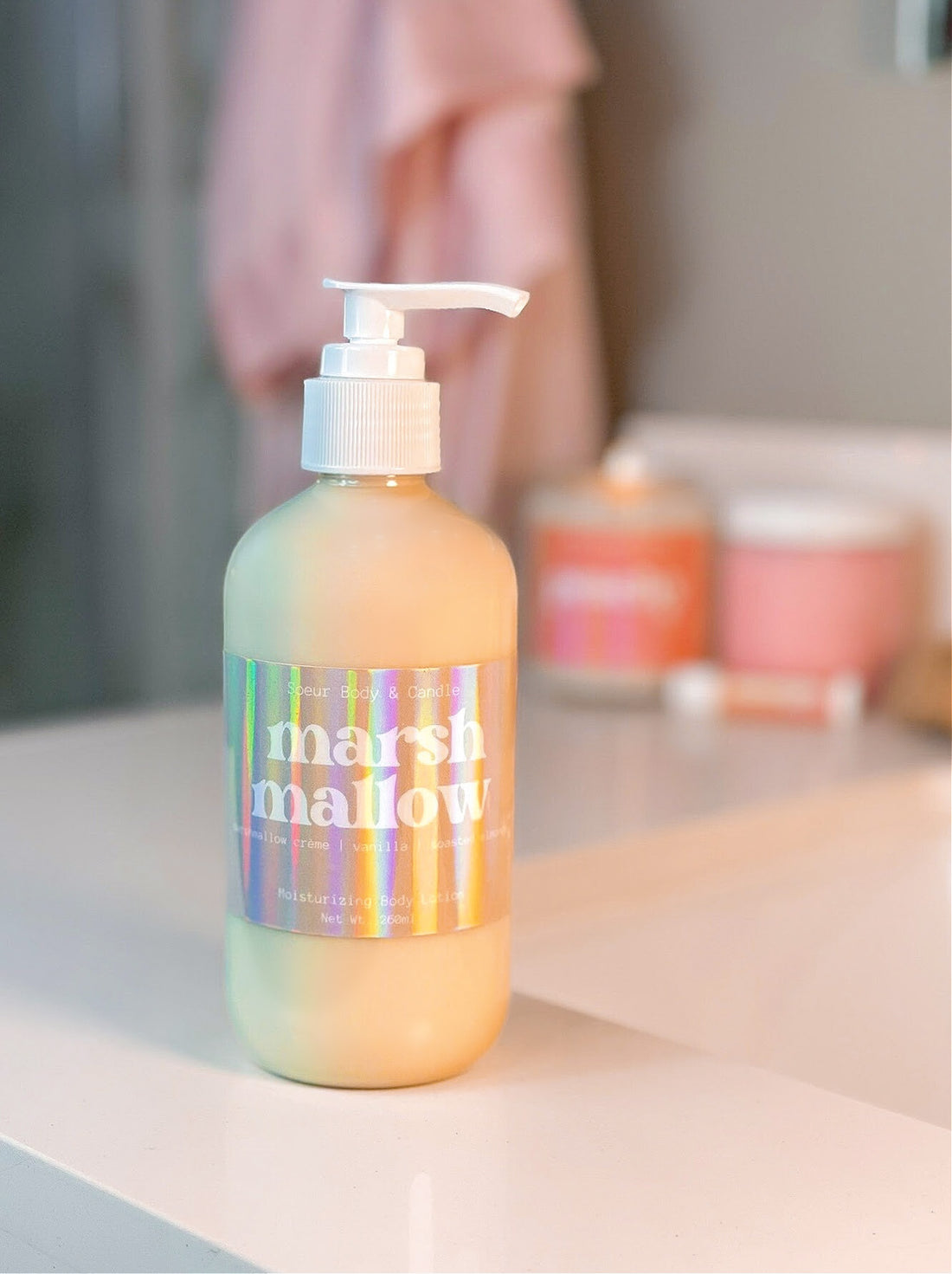 Marshmallow Body Lotion sitting on a bathroom counter, featuring hemp oil for moisturizing with a marshmallow crème, vanilla, and toasted almond scent. Cruelty-free, vegan, and sustainably packaged.