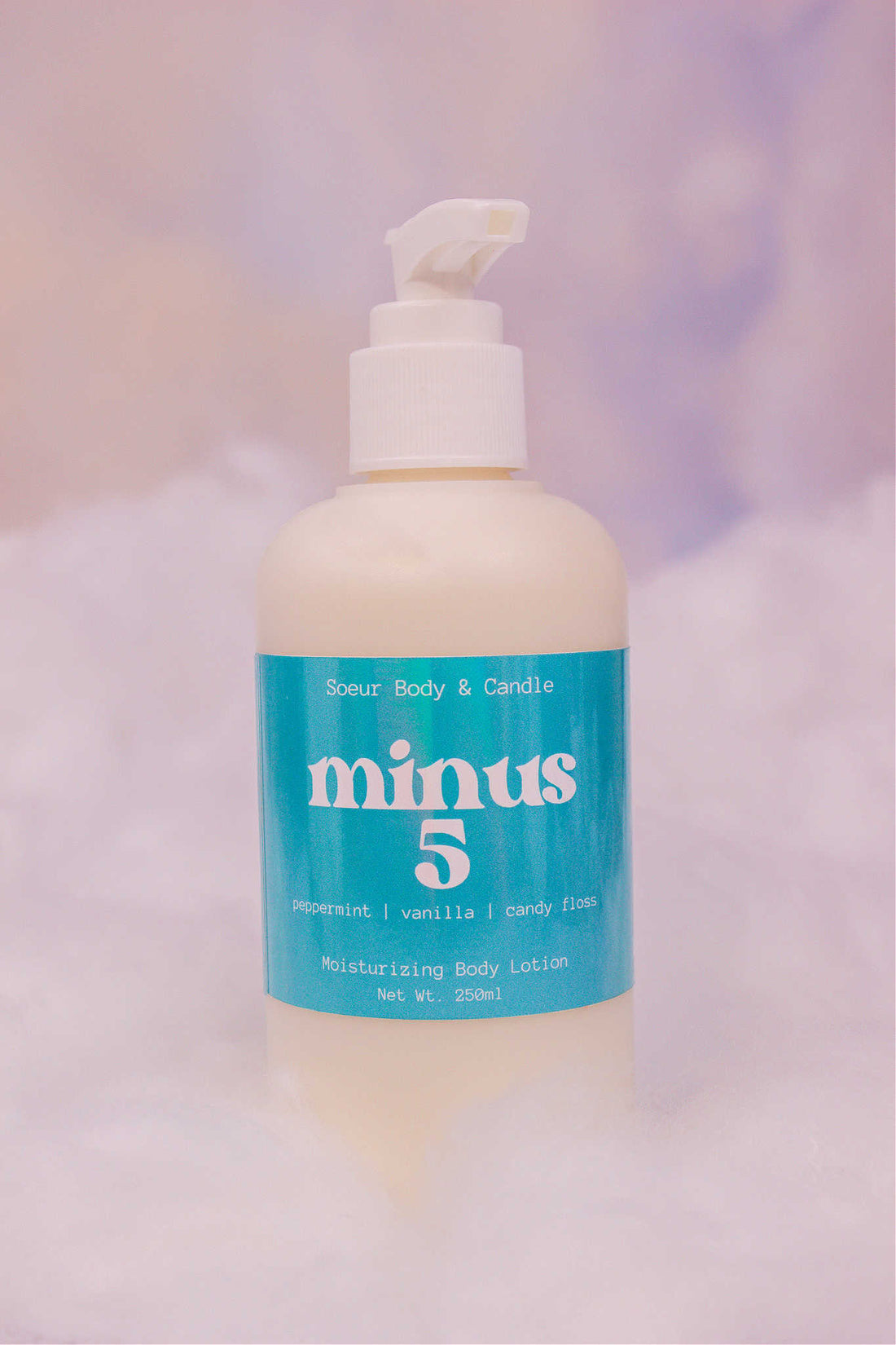 Minus 5 body lotion sitting in fake snow against a cloudy background. Featuring notes of peppermint, vanilla, and candy floss.