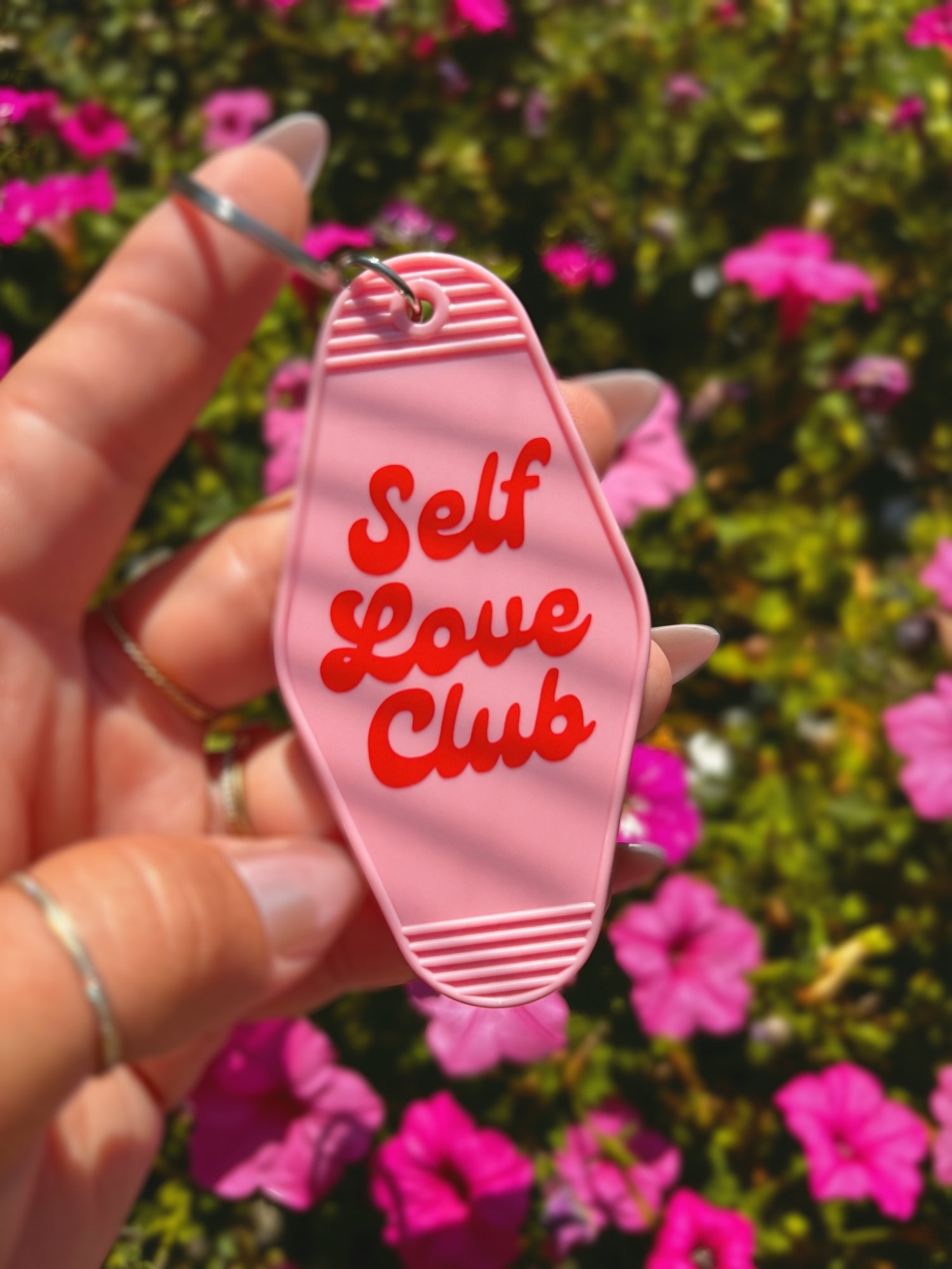 A hand holds a pink motel-style keychain with the words &