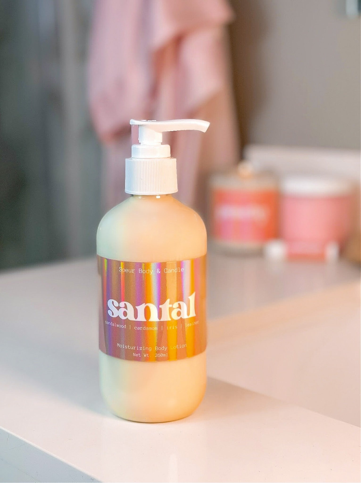 Santal Body Lotion sitting on a bathroom counter, featuring hemp oil for moisturizing with a sandalwood, cardamom, iris, and leather scent – a dupe of Santal 33 by Le Labo. Cruelty-free, vegan, and sustainably packaged.