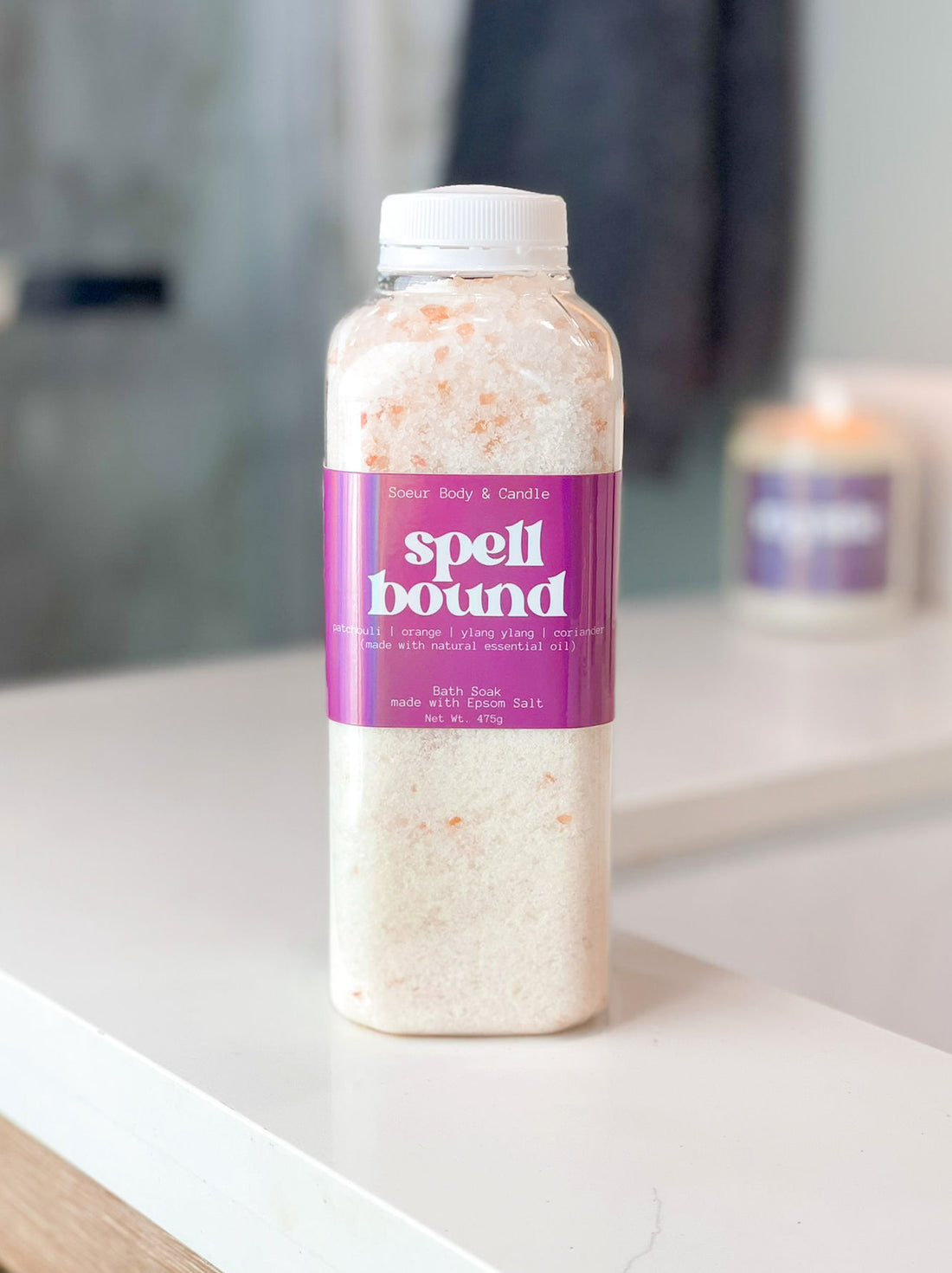 Spellbound bath soak made with an essential oil mix of orange, ylang ylang, patchouli, and coriander, on a bathroom counter, featuring Epsom Salt for muscle relaxation and Himalayan Pink Salt, rich in essential minerals like potassium, calcium, and magnesium.