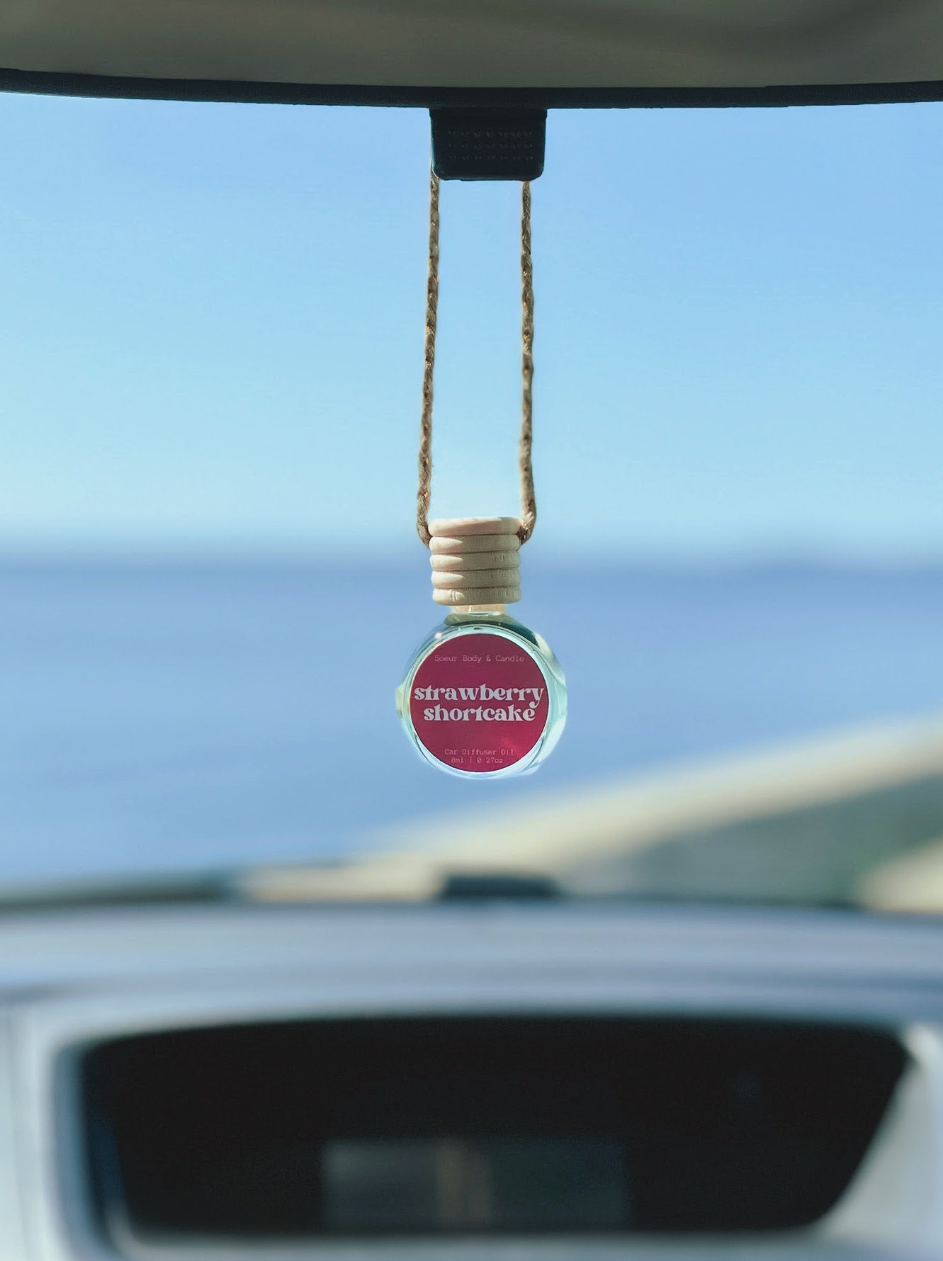 Strawberry Shortcake Diffuser Oil hanging from a rearview mirror, offering a balanced, long-lasting fragrance of sweet strawberry, sugar, and vanilla. Perfect for cars, closets, lockers, and more.