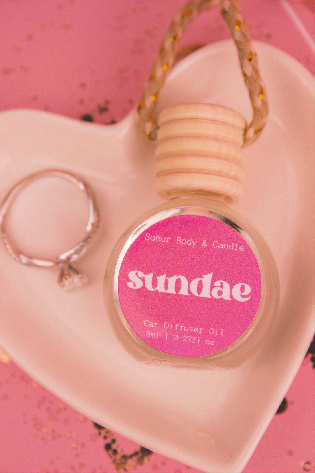 Close-up of Sundae car diffuser in a jewelry dish with a ring beside it, featuring notes of sweet cream, vanilla,  and sugary waffle cone.