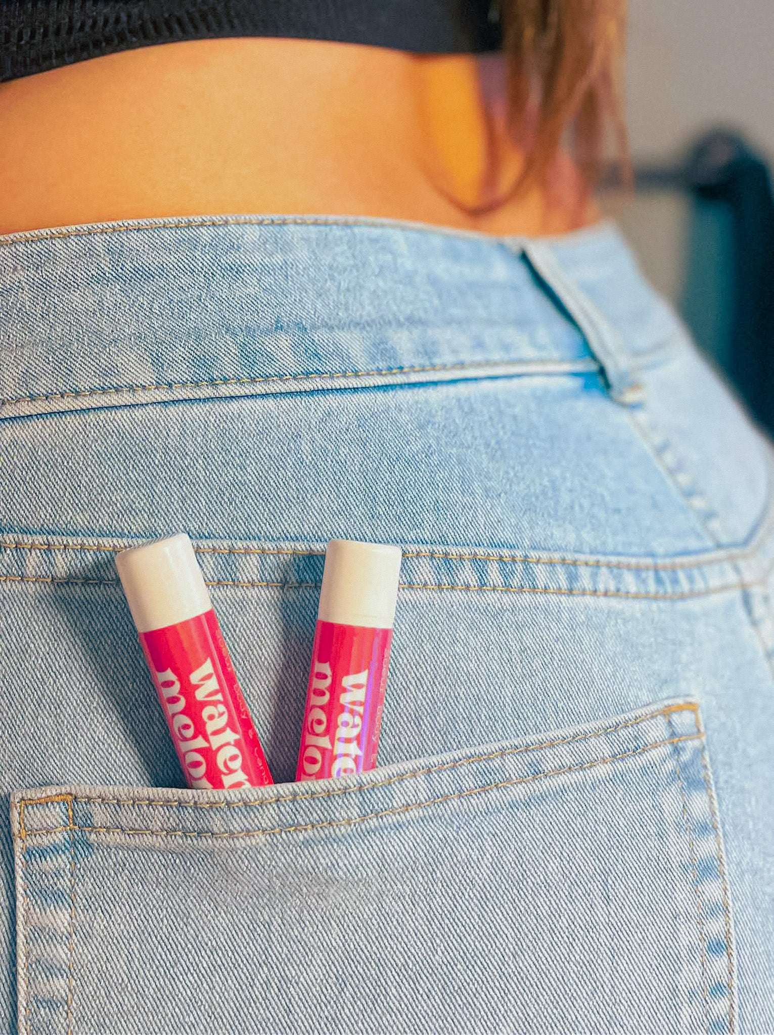 Watermelon lip balm in a tube, made with Ontario beeswax, coconut oil, and castor oil, offering softness and hydration.