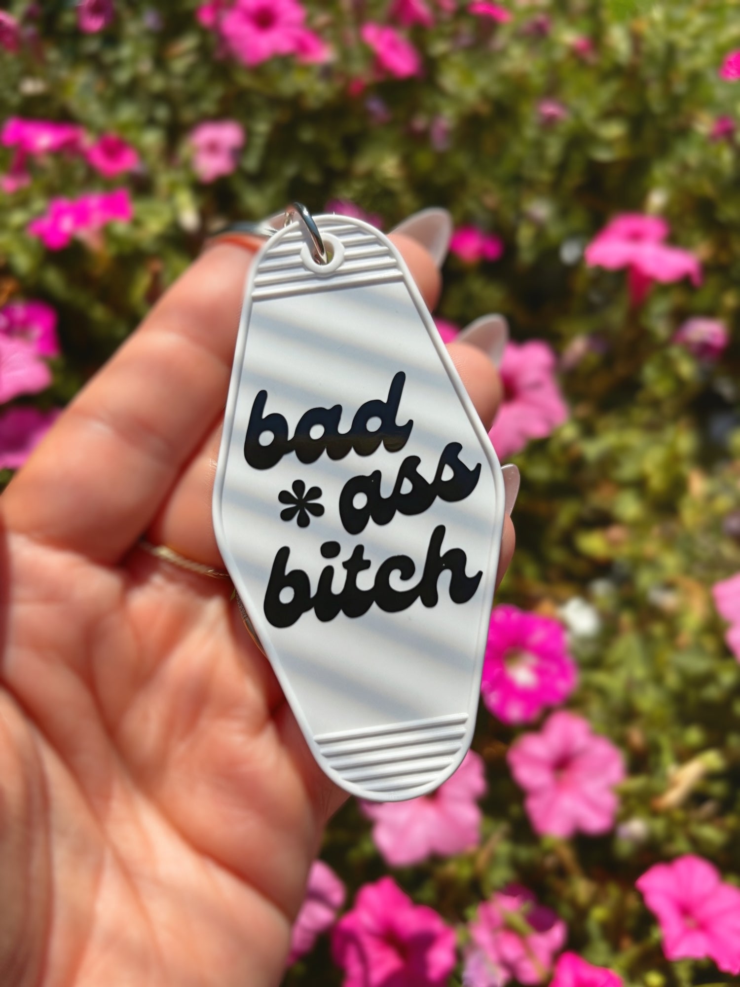 A hand holding a white motel-style keychain with black text that reads &